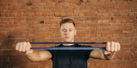 Man using resistance band against brick wall for fitness exercise.
